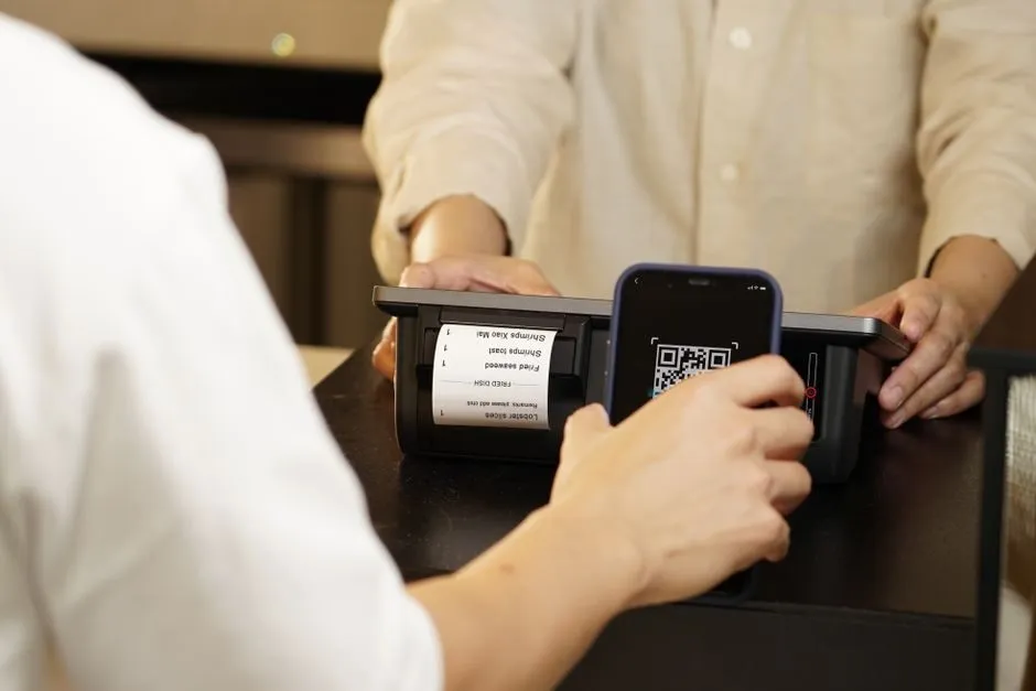 Khách hàng dùng điện thoại quét mã QR tại quầy thanh toán
